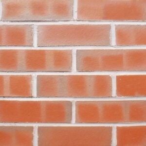 A diisplay panel image of brick slips laid in a stagger bond. The bricks are red with multi coloured bar marks. They are a modern manufactured style with very accurate dimensions and regular, crisp edges and a smooth surface finish. The panel is pointed with a mid grey mortar.