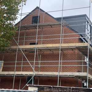 A house under construction with scaffold boards around the front elevation. It is built using brick slips as the brick veneer.