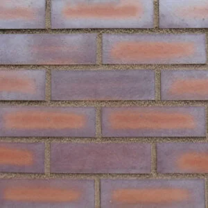 A panel of brick slips bonded on to a brick slip tracking sheet. The bricks are a smooth finish with multi-coloured red and blue/silver tones. The panel is pointed in a mid brown pointing mortar