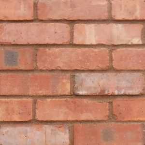 A panel of brick slips. The bricks are reclaimed, light orange and buff in colour with chipped edges. They are pointed in a dark sandstone pointing mortar