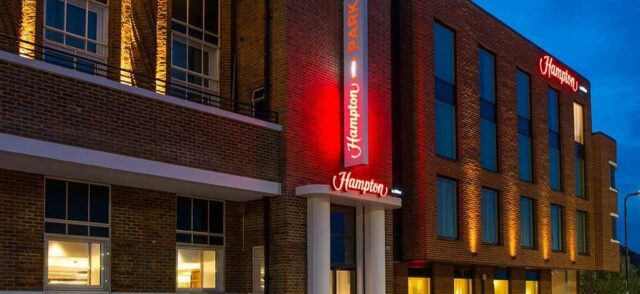 Hampton by Hilton Park Royal Hotel in London as seen at night with up lighting of the brickwork. The surface texture of the bricks is accentuated by the oblique lighting